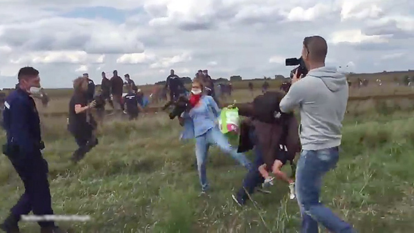 女摄像师在众目睽睽之下伸出左脚将难民连小孩一起绊倒。